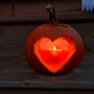 Photo of a pumpkin carved into a heart, with a candle inside.