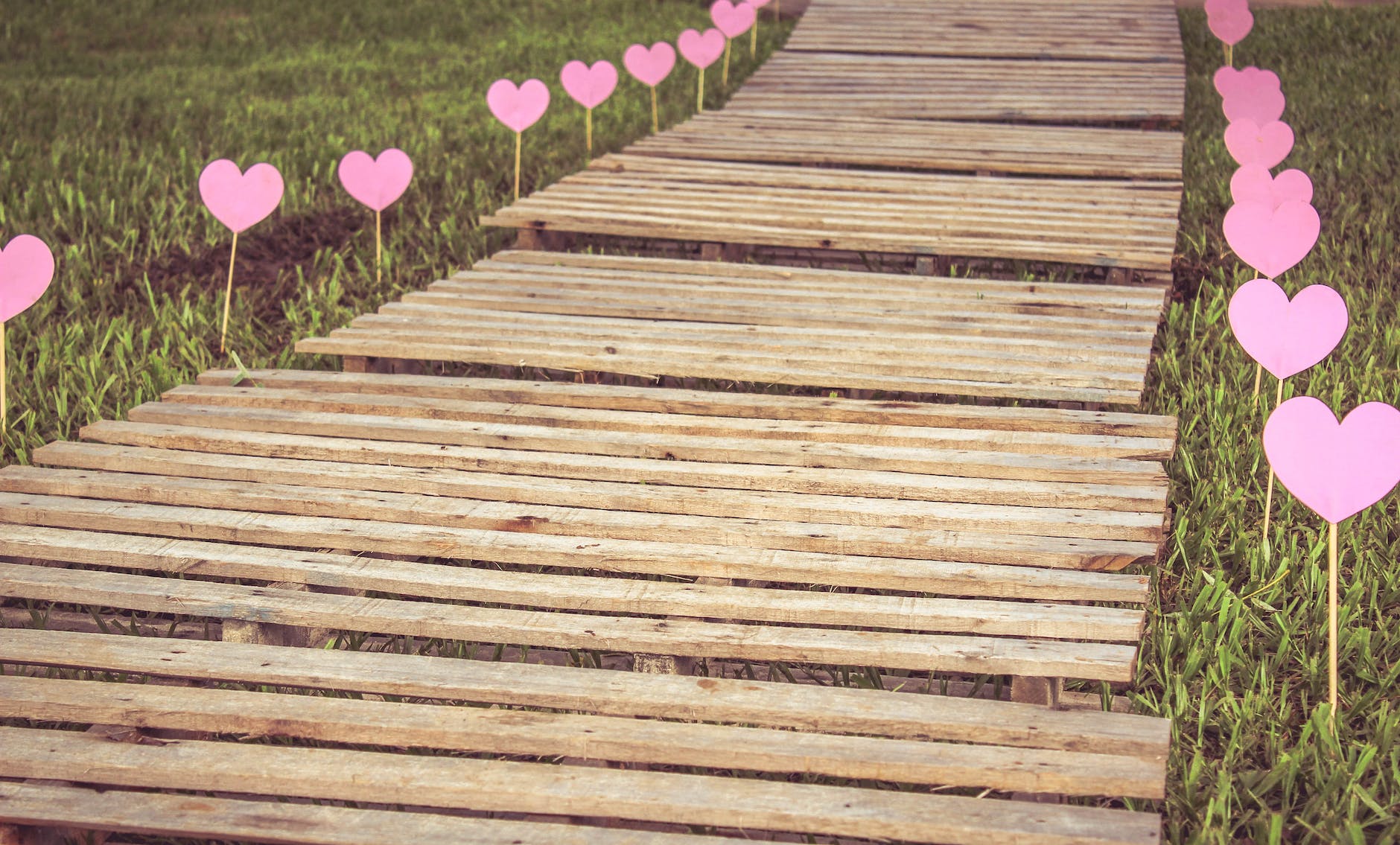 A wooden boardwalk with hearts lining it on either side.