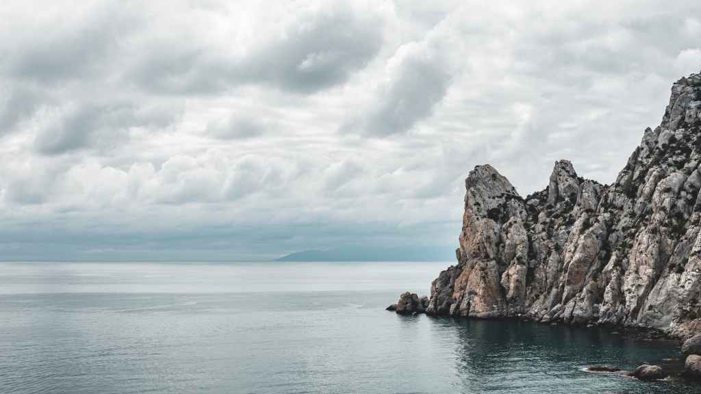 Rough cliffs on the ocean, with dark clouds filling the sky.