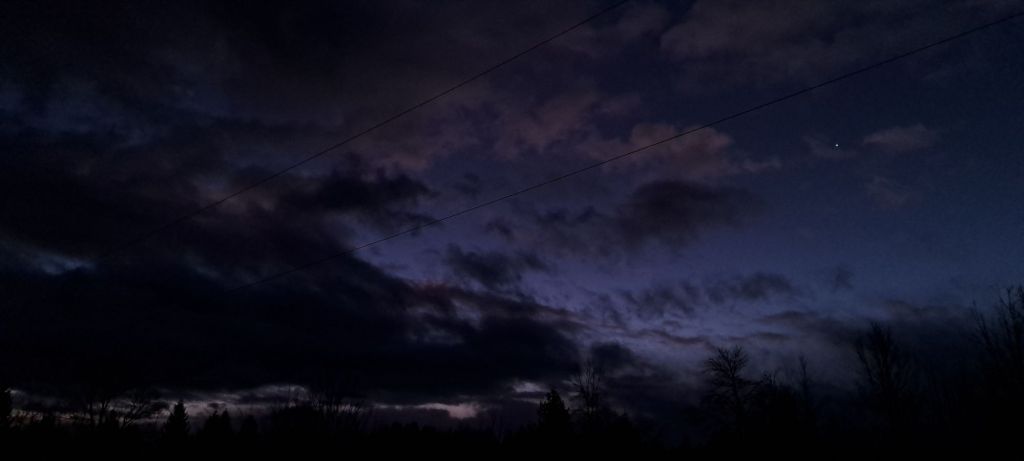 Dark, early morning sky, with a few stars and clouds.
