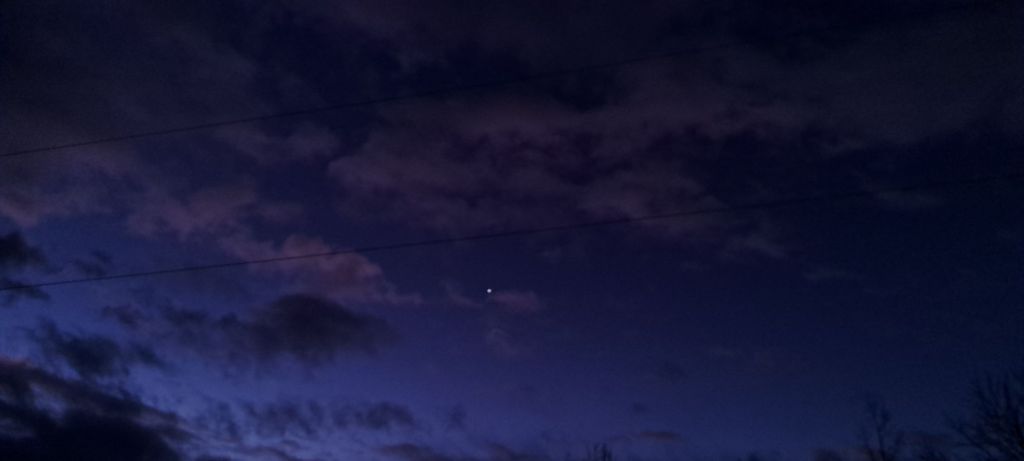 Dark, early morning sky, with a few stars and clouds.