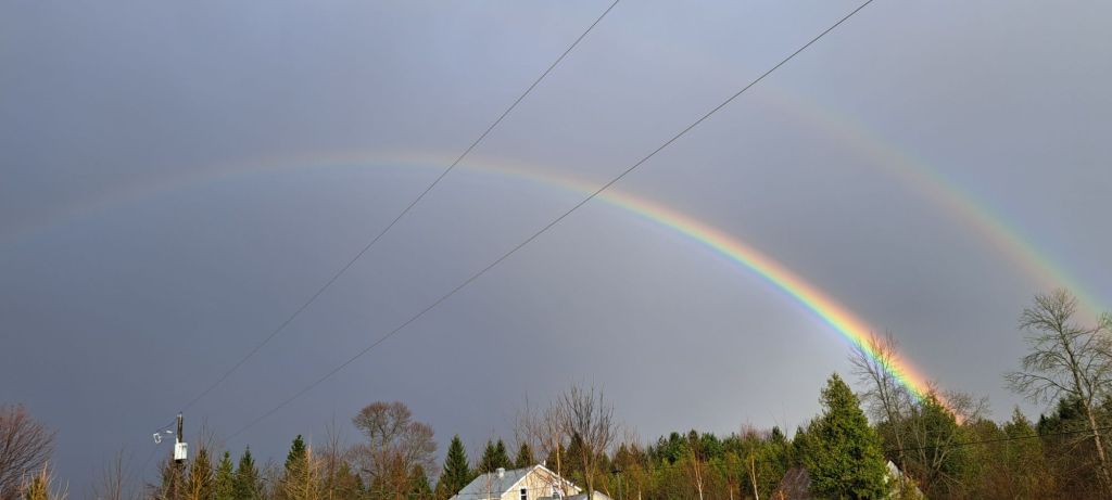 A double rainbow against a cloudy sky