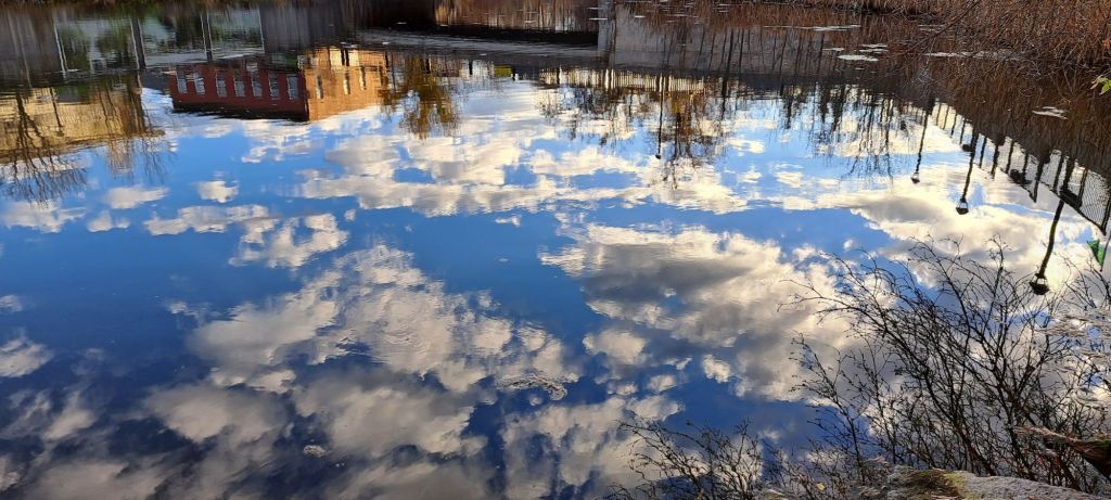 A blue sky with white clouds reflected in water.