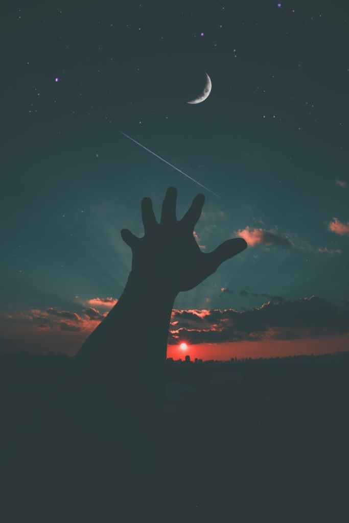Hand reaching out to the night sky