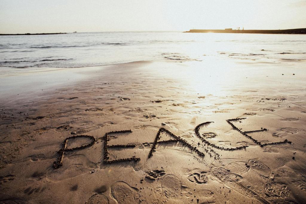 Sand on a beach with the word, peace, written in it.